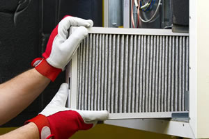 Homeowner replacing a 1-inch HVAC filter in a Hickory, NC hallway return grille